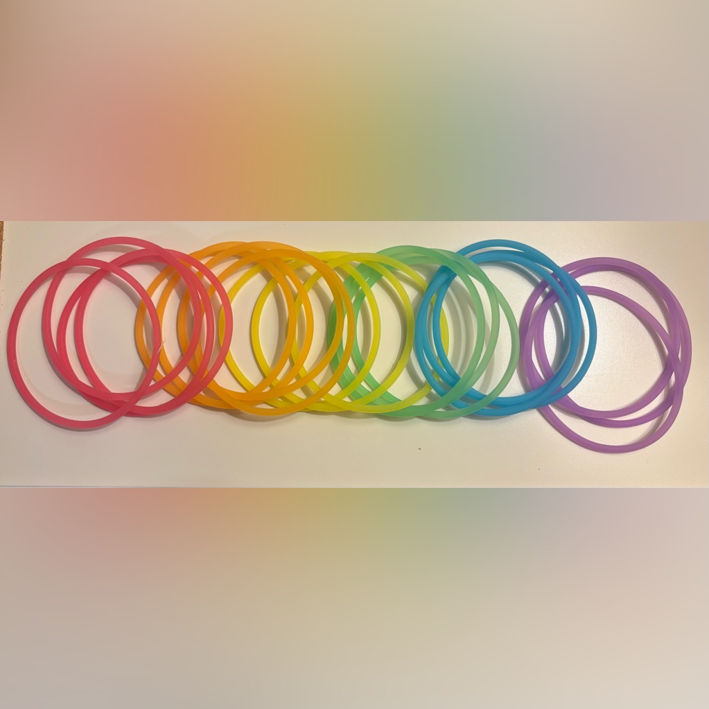 A rainbow set of thin jelly bangle bracelets laid out in a row